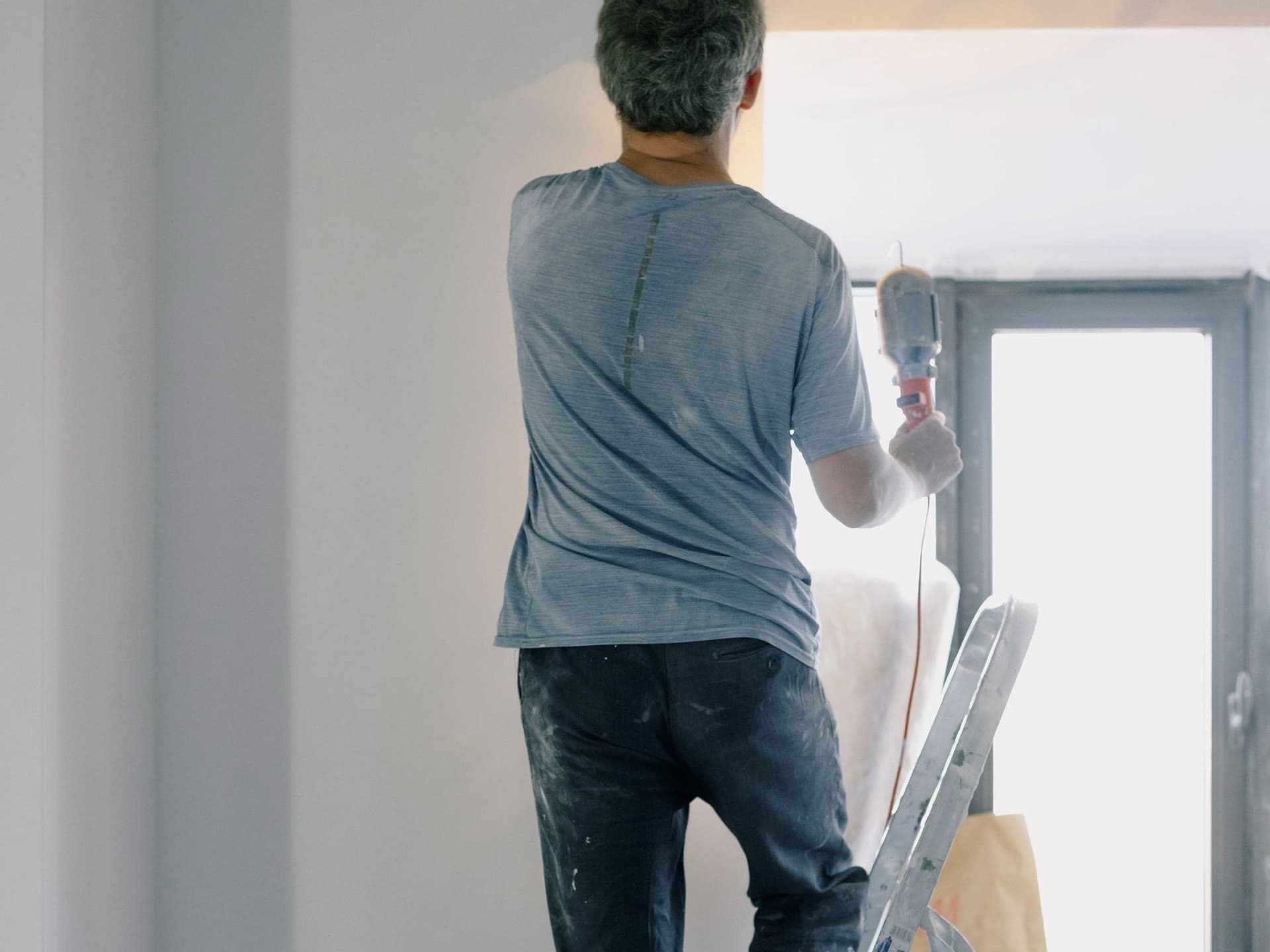 Jose Argueta of J.C Home Services on a ladder, finishing a wall